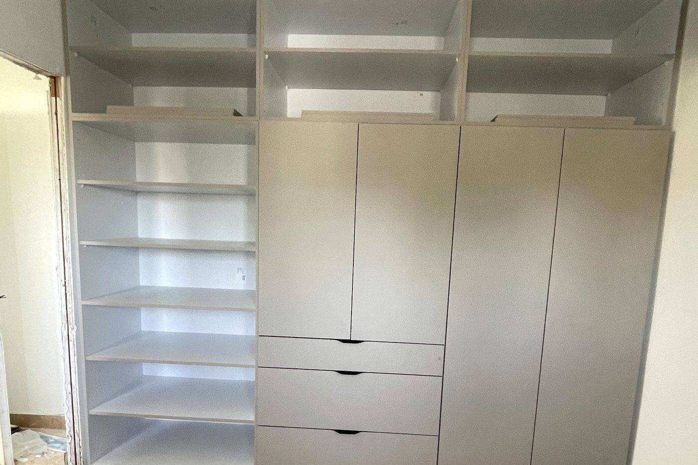 ארון קיר מרצפה עד תקרה בהתקנה, מבטחים – תאים פתוחים, מגירות ודלתות בגוון בז׳ בהיר